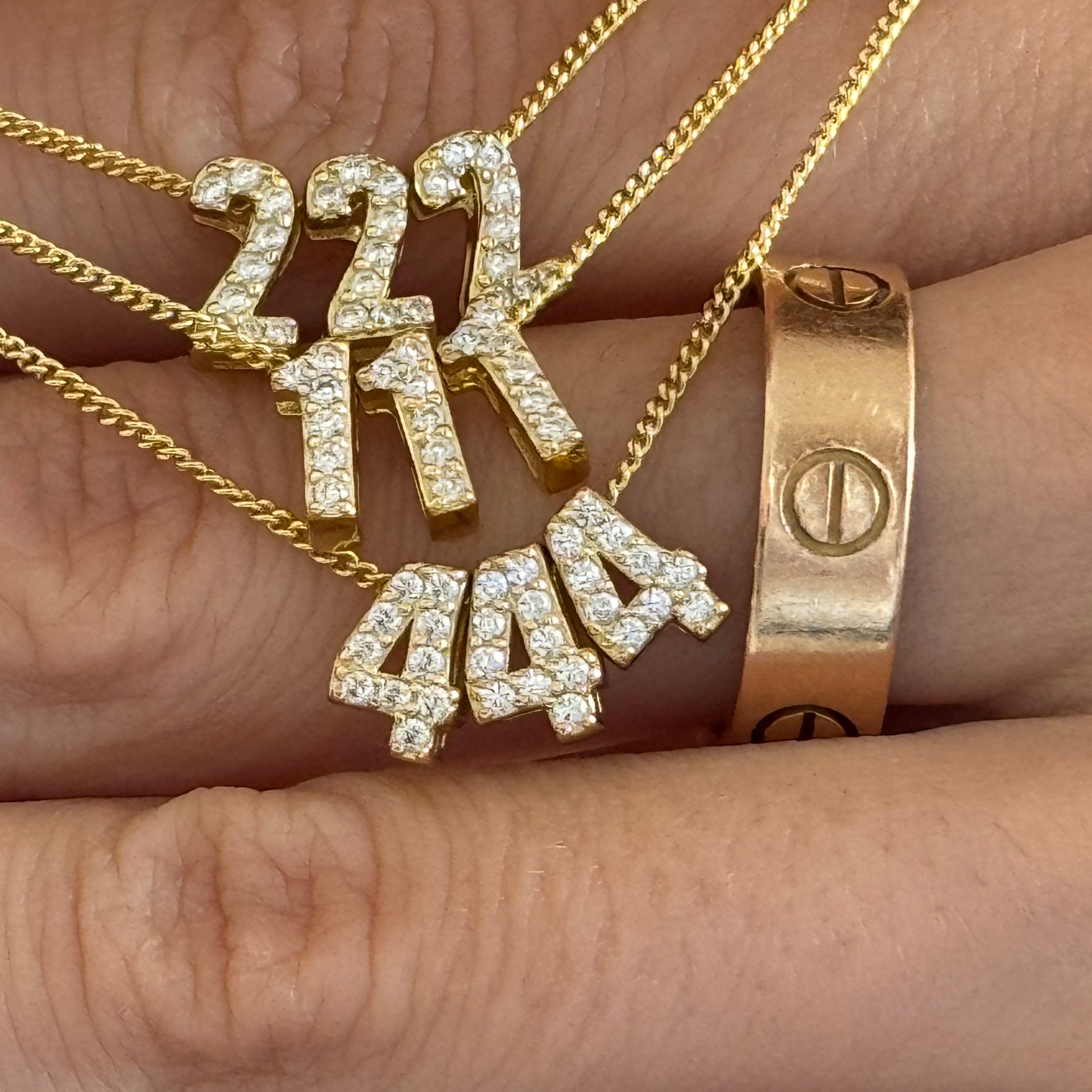 Baby Angel Number Necklaces in 222, 111 and 444 held in the hand