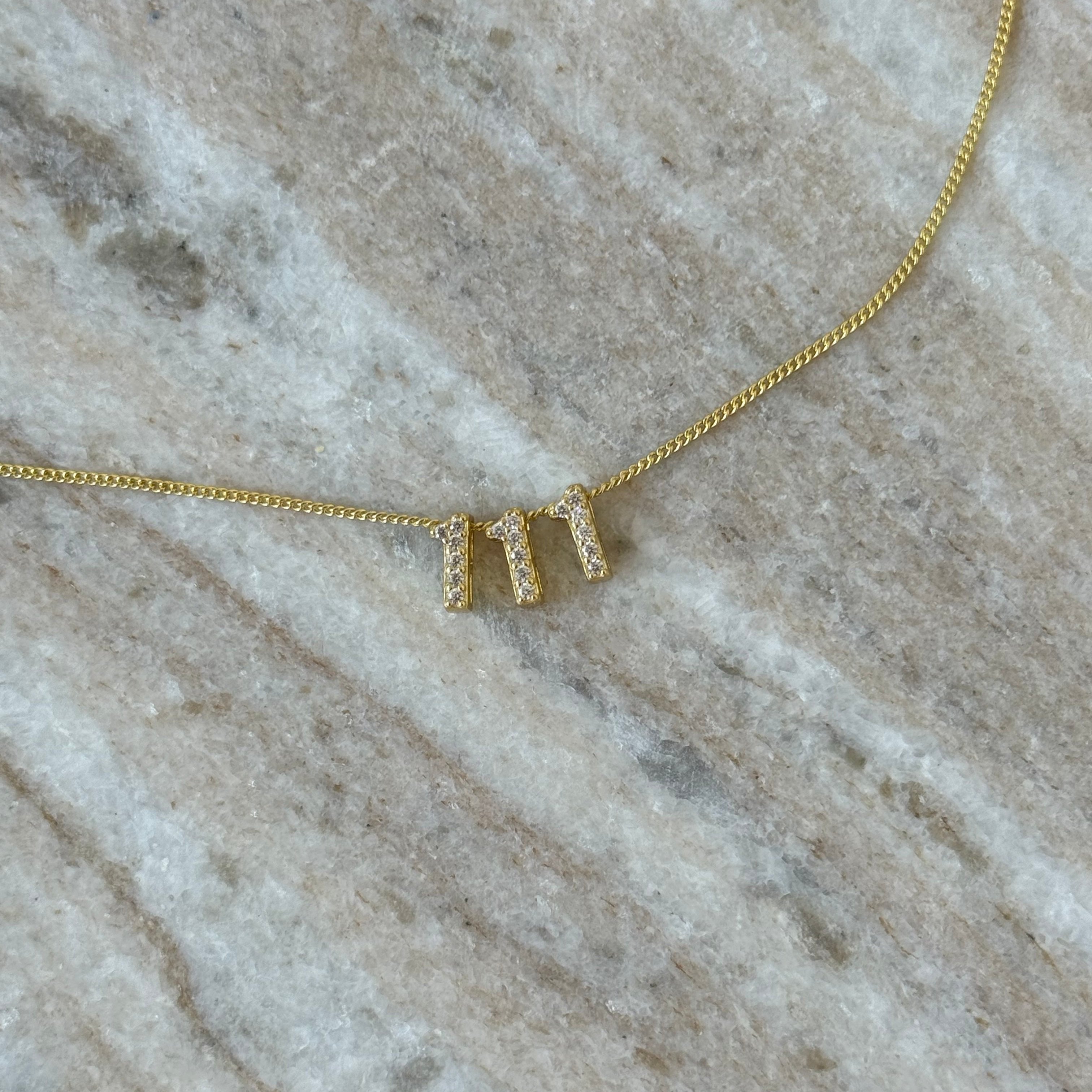 Close-up of the Baby Angel Number Necklace in 111 on marble