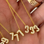 Hand holding Baby Angel Number Necklaces in 777 and 333