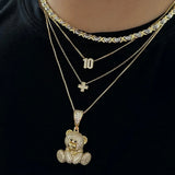 Baby Cross Necklace layered with a number necklace and iced teddy necklace on a black tee