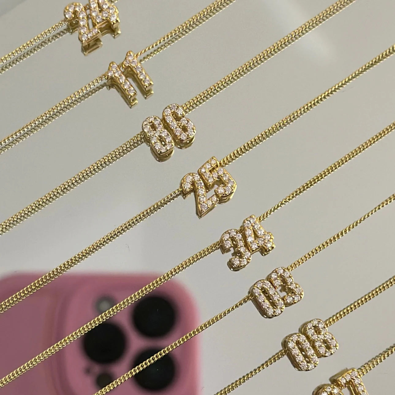 Baby CZ Double Digit Number Necklaces in gold laid out with different numbers