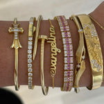 Wrist stack with a Baby Script Nameplate bracelet, cross cuff and tennis bracelets