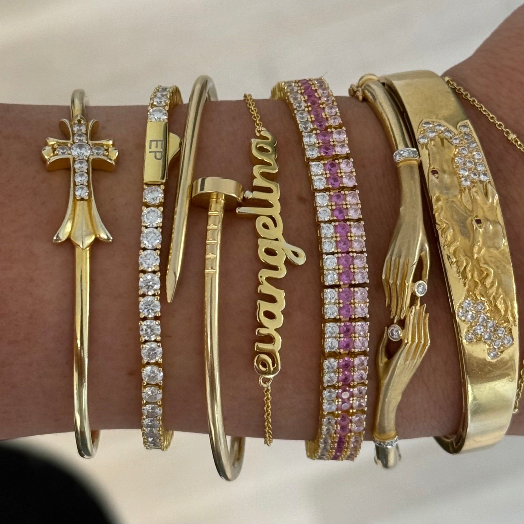 Wrist stack with a Baby Script Nameplate bracelet, cross cuff and tennis bracelets