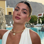 Model by a pool wearing a birthstone pendant on a gold cuff necklace