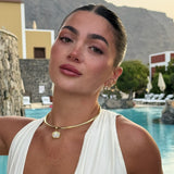 Model by a pool wearing a birthstone pendant on a gold cuff necklace