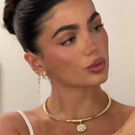 Model wearing a birthstone pendant on a gold cuff necklace with drop earrings