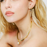 Model wearing a birthstone pendant on a gold cuff necklace with drop earrings