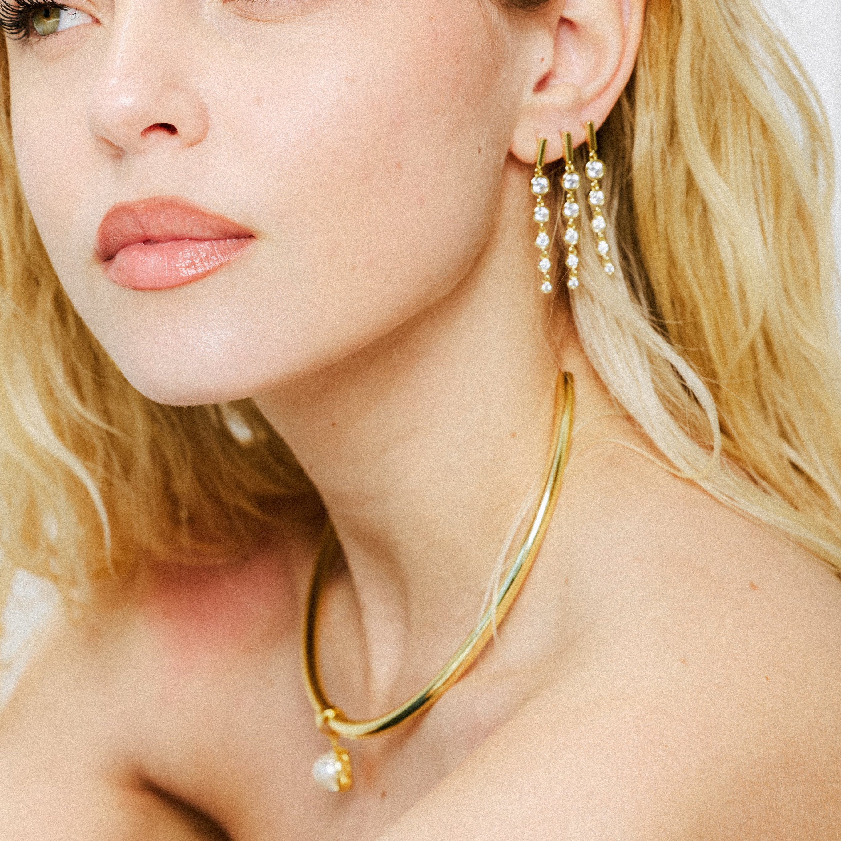 Model wearing a birthstone pendant on a gold cuff necklace with drop earrings