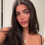 Model wearing a gold CZ script nameplate layered with an iced script letter necklace