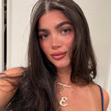 Model wearing a gold CZ script nameplate layered with an iced script letter necklace