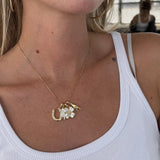 Gold good luck charm necklaces layered over a white tank, with a horseshoe and clover