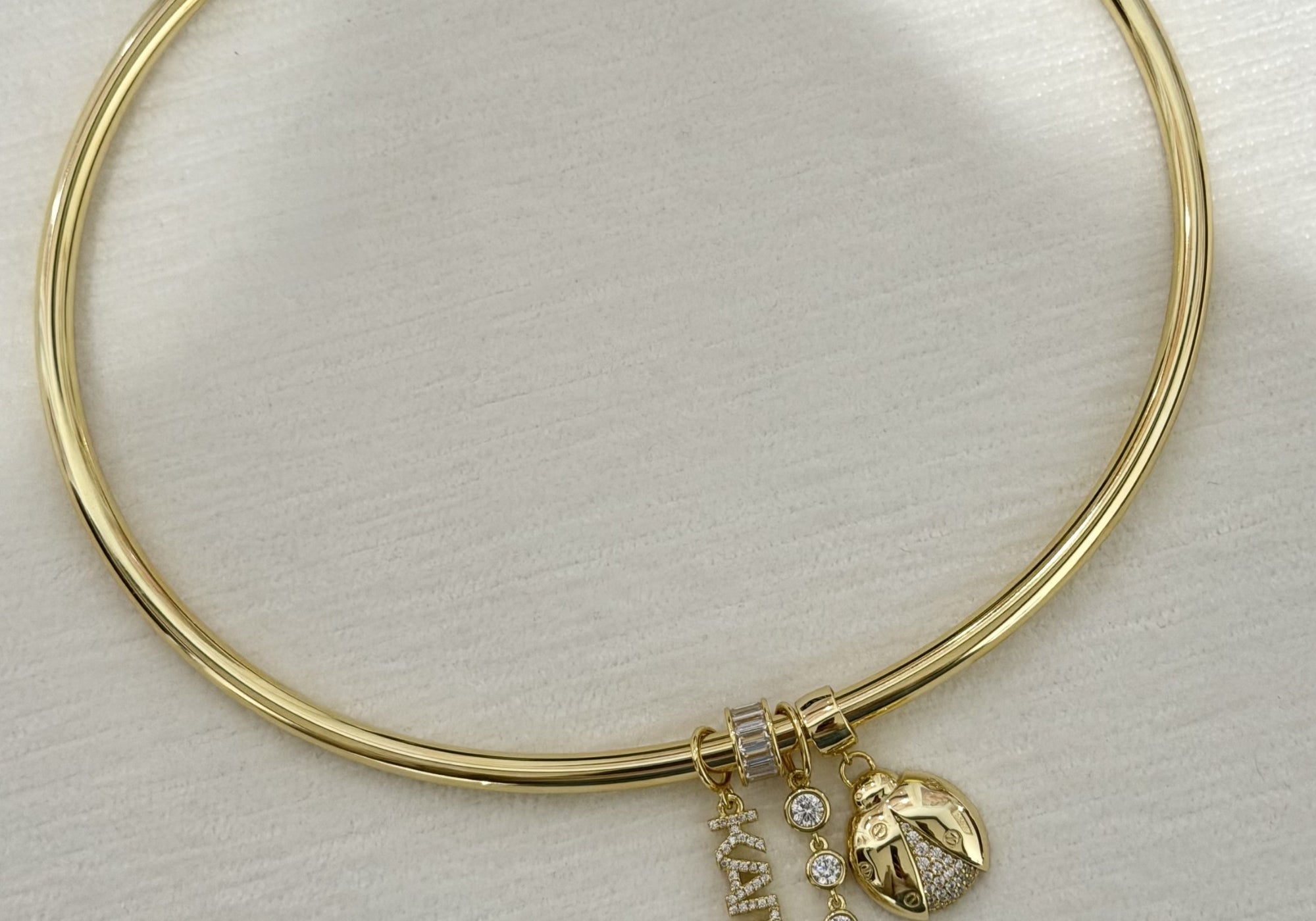 Cuff necklace with nameplate charms on a table