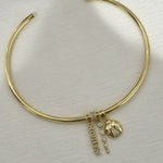 Cuff necklace with nameplate charms on a table