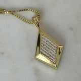 Close-up of the gold CZ Taylor pendant on a box chain on marble