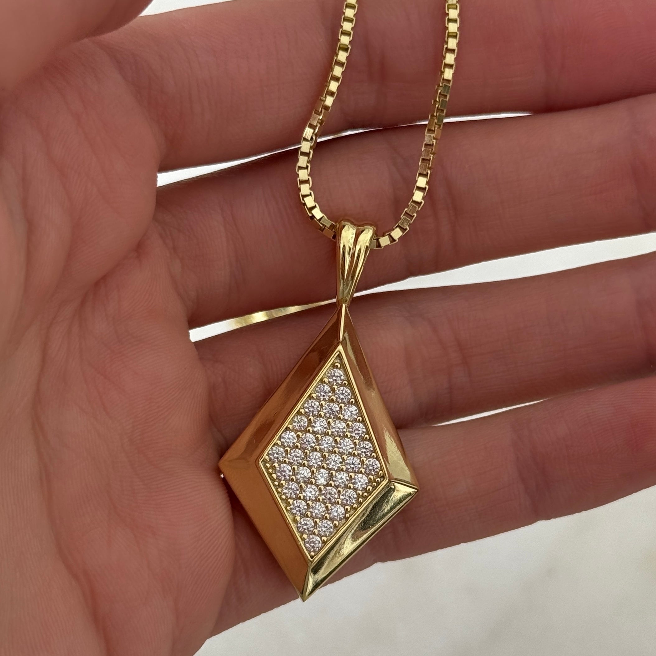 Hand holding the gold CZ Taylor Necklace on a box chain