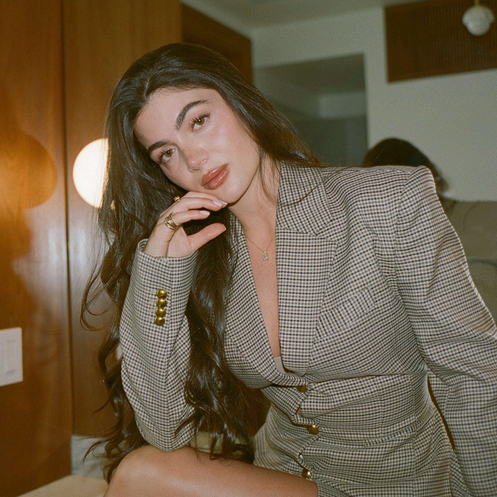Model seated in a houndstooth blazer wearing the Classic Pear Diamond Necklace