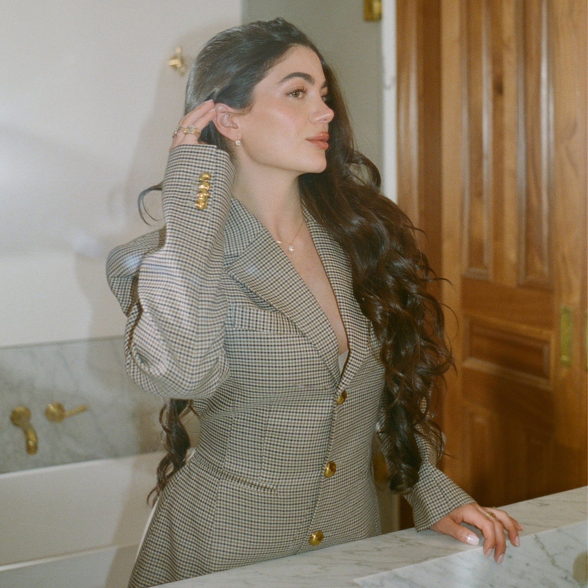Model in a houndstooth blazer touching her hair, wearing the Classic Pear Diamond Necklace