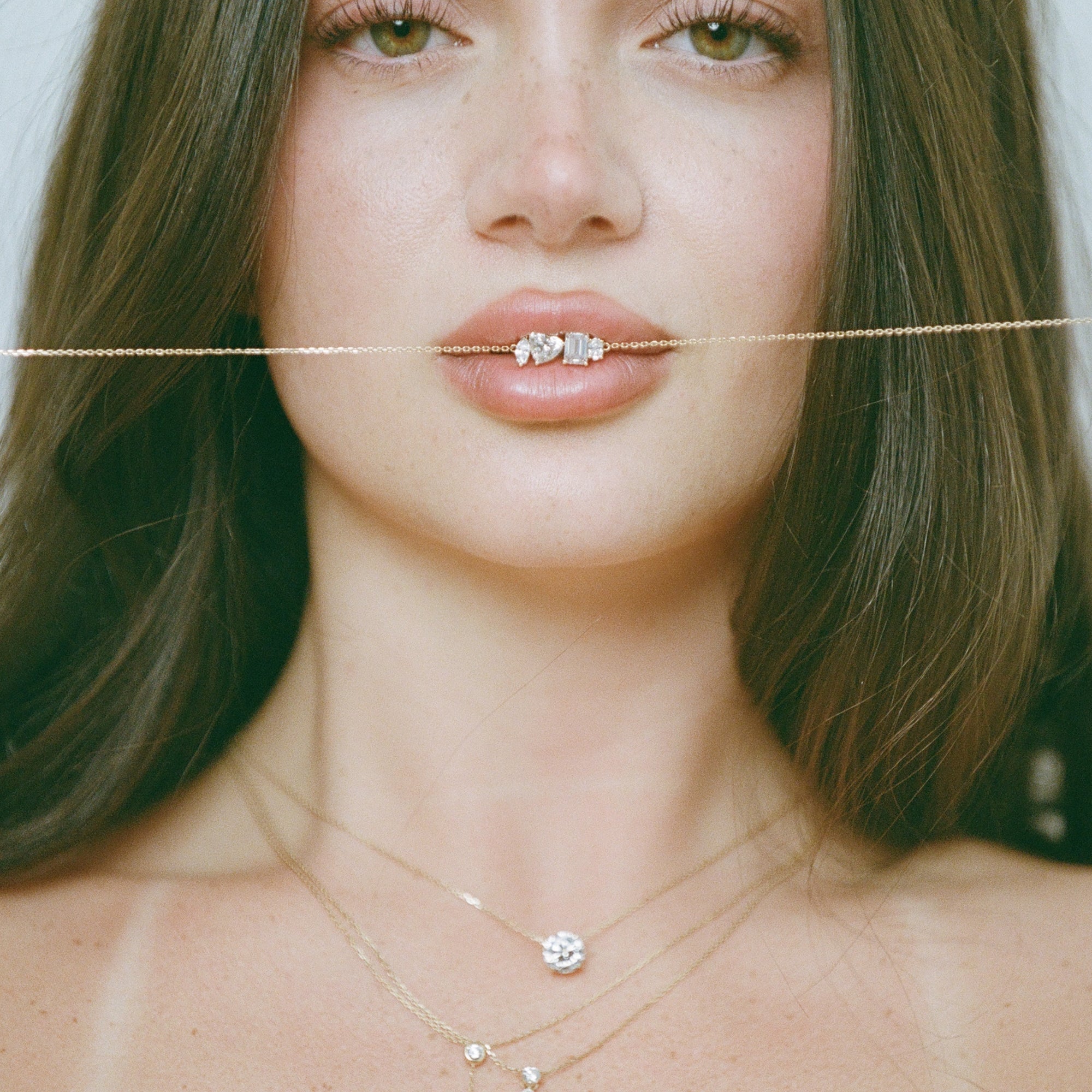 Model holding a chain in her teeth while wearing the Classic Round Diamond Necklace in 14K solid gold