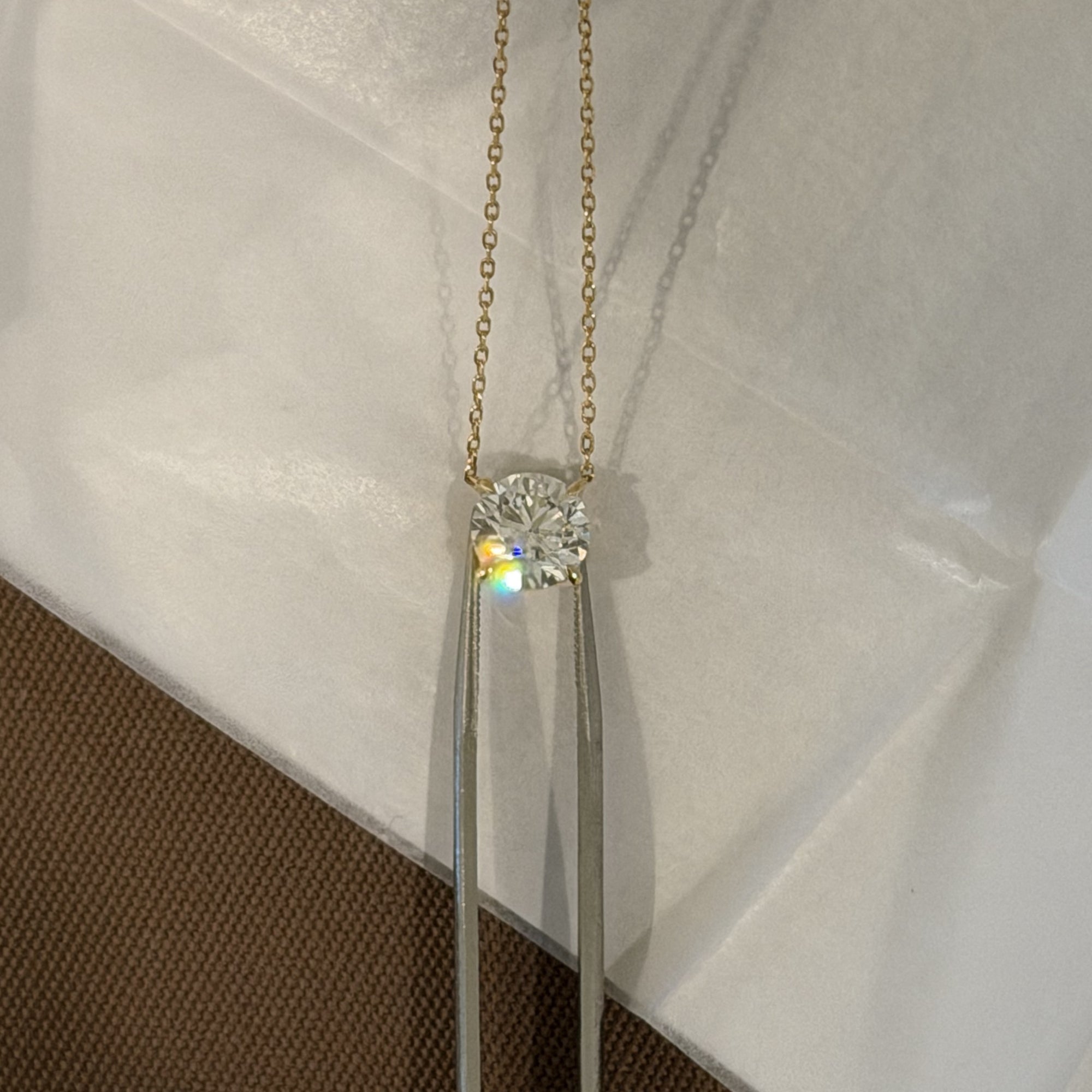 Classic Round Diamond Necklace hanging against white linen, fine jewelry in 14K solid gold