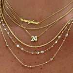 Layered gold Dainty Chains with a script nameplate and number pendant