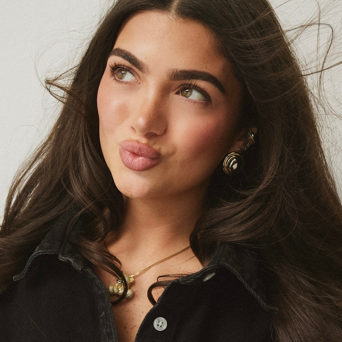 Model in black wearing the Iced Jumbo EP Teddy Necklace and gold earrings