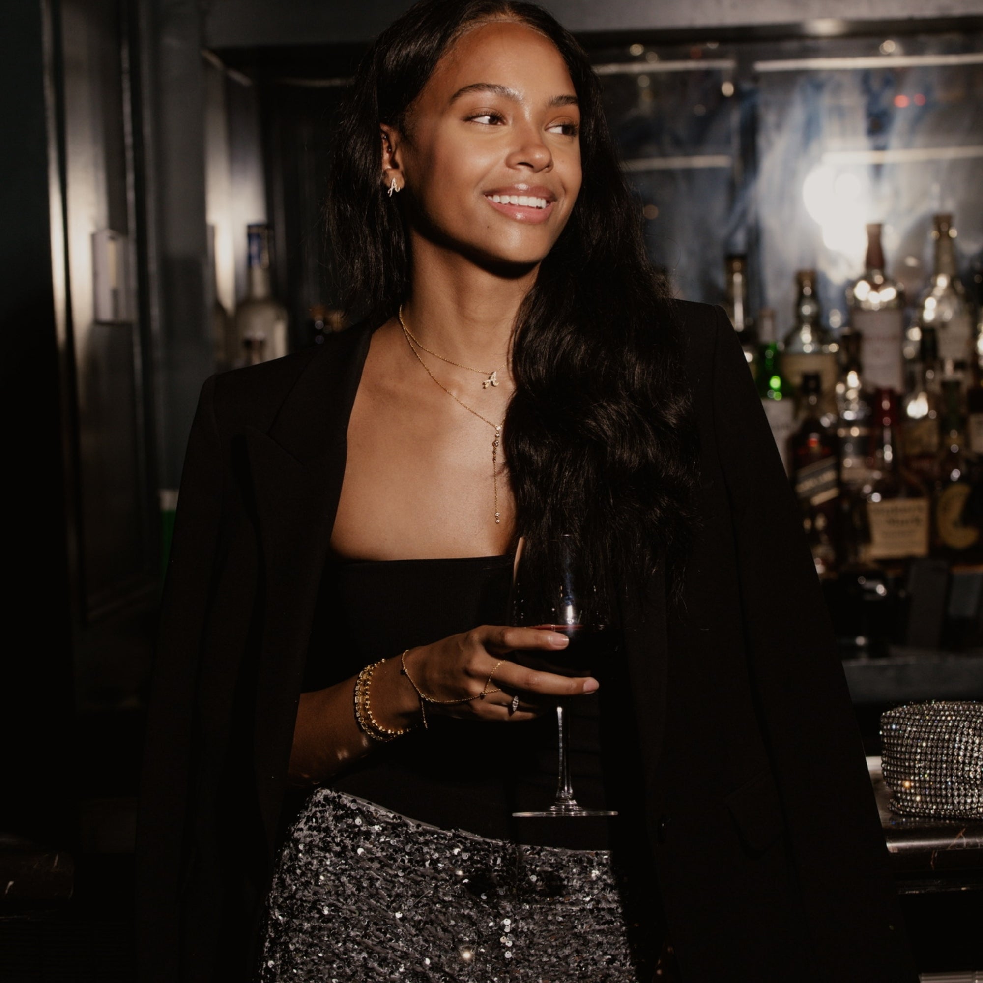 Woman at a night out wearing a dainty iced script initial necklace