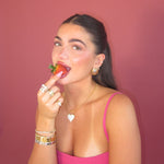 Model in a pink top eating a strawberry, wearing the Iced Jumbo Heart Necklace