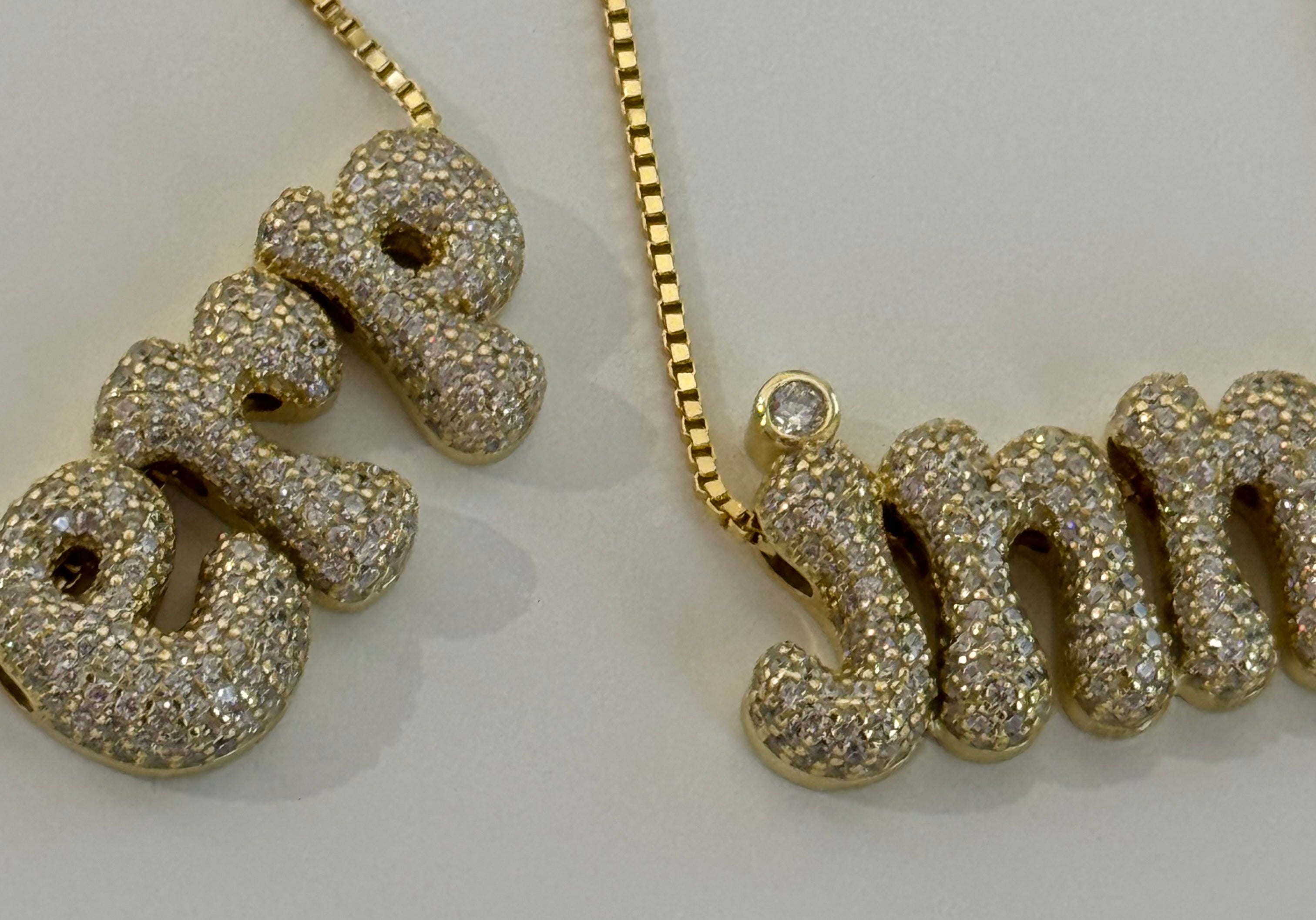 Close-up of gold Iced Jumbo Initials Necklaces in erp and jnm