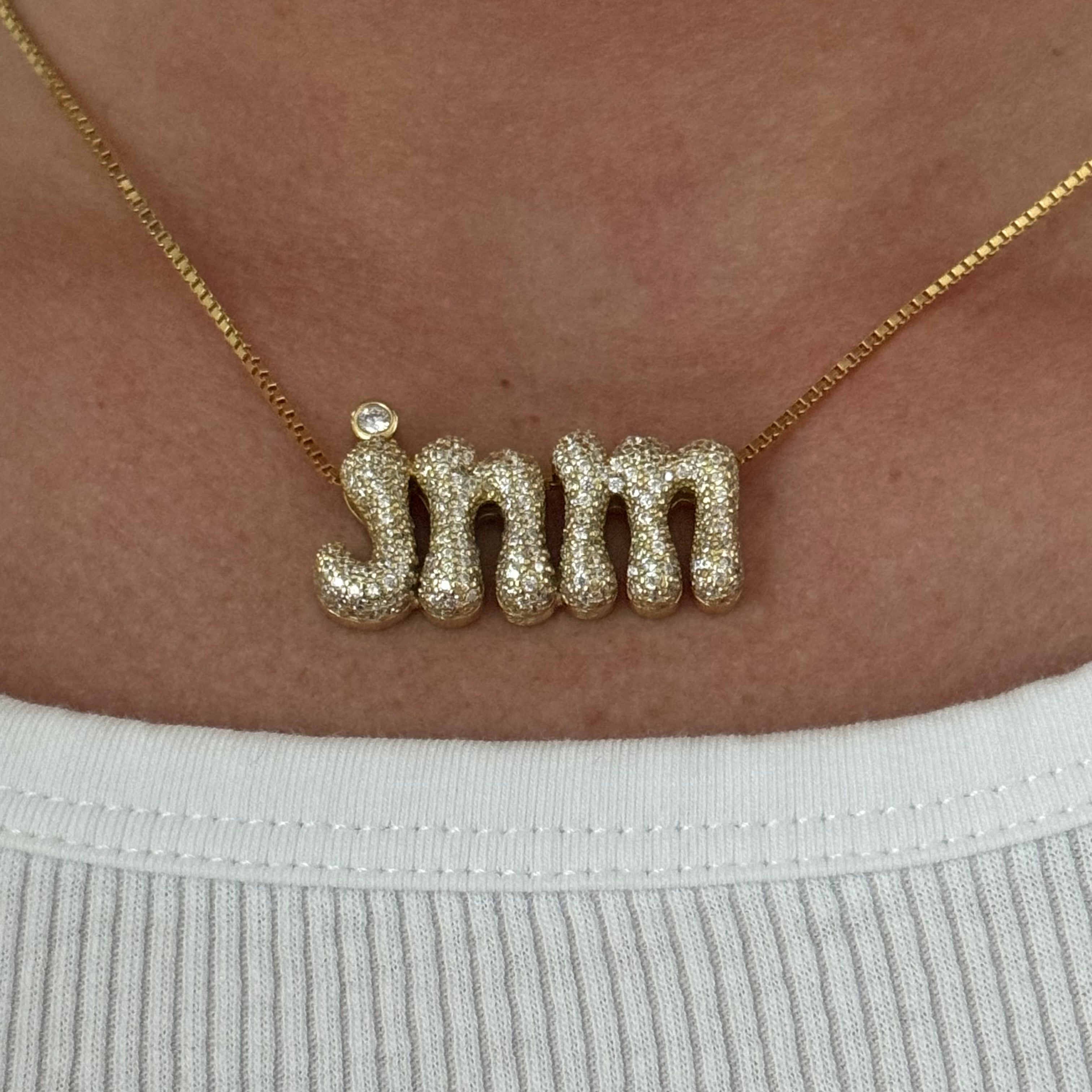 Model wearing the gold Iced Jumbo Initials Necklace in jnm with a white tee
