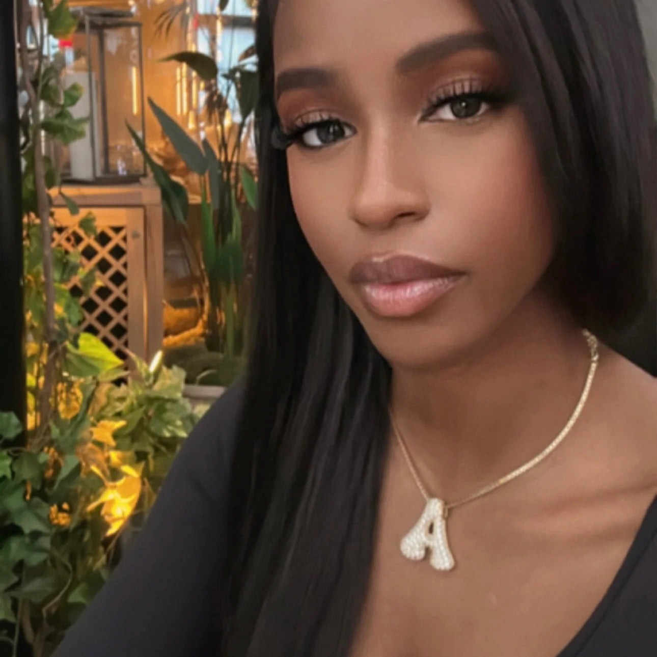Woman wearing a gold iced jumbo letter A necklace