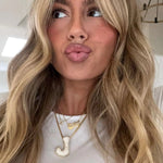 Woman wearing a gold iced jumbo letter J necklace