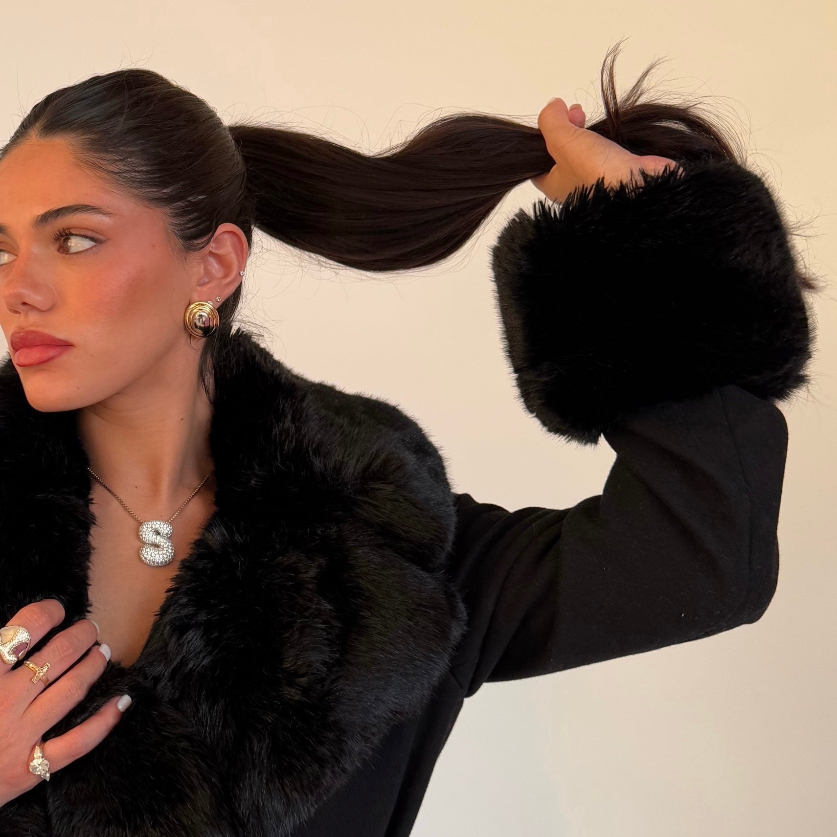 Model wearing an iced jumbo letter necklace with a black faux fur coat
