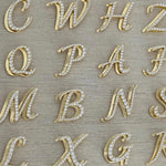 Iced Jumbo Script letters in gold laid out, showing different initials