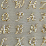 Iced Jumbo Script letters in gold laid out, showing different initials