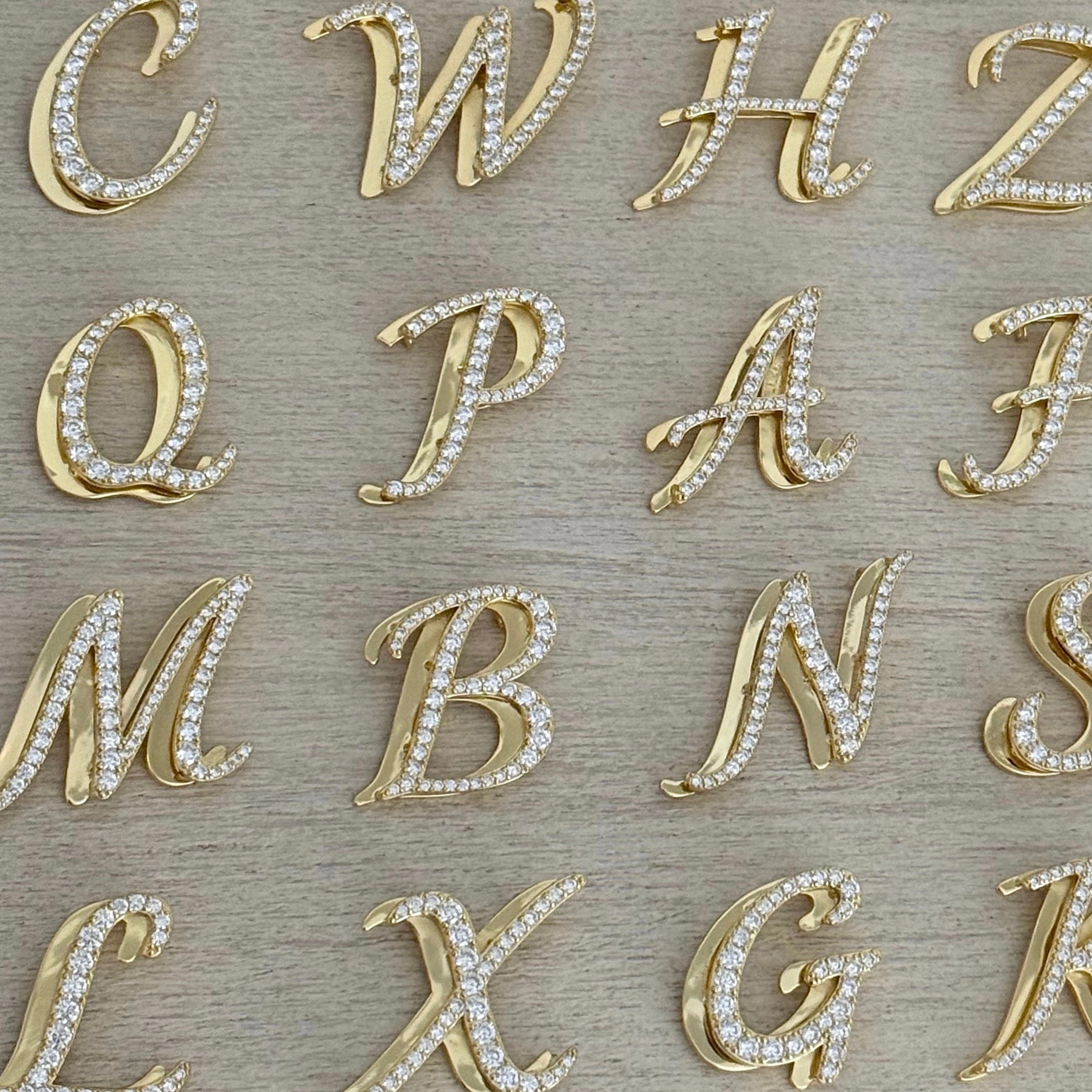 Iced Jumbo Script letters in gold laid out, showing different initials