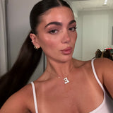 Model wearing a gold iced medium jumbo letter E necklace