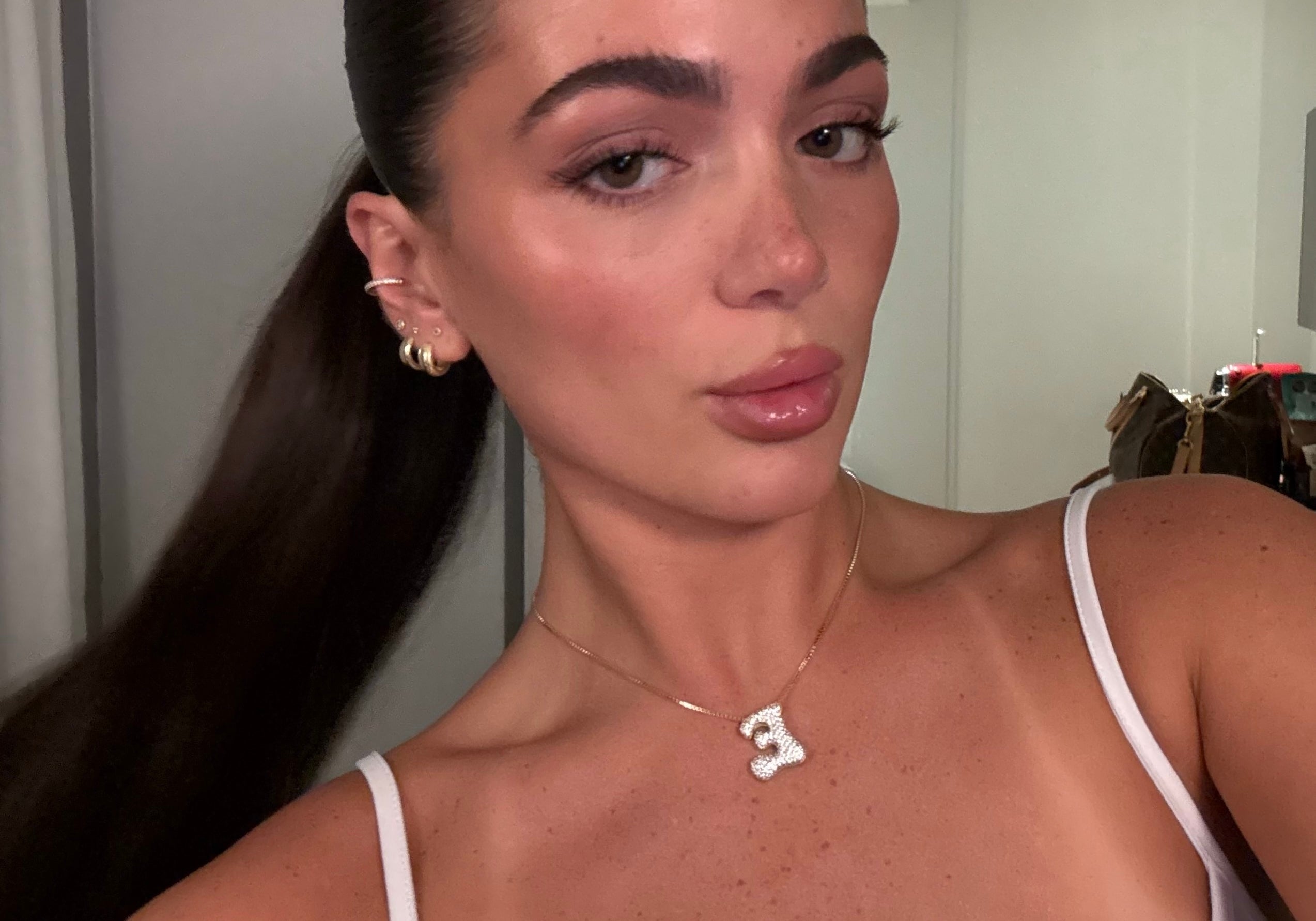 Model wearing a gold iced medium jumbo letter E necklace