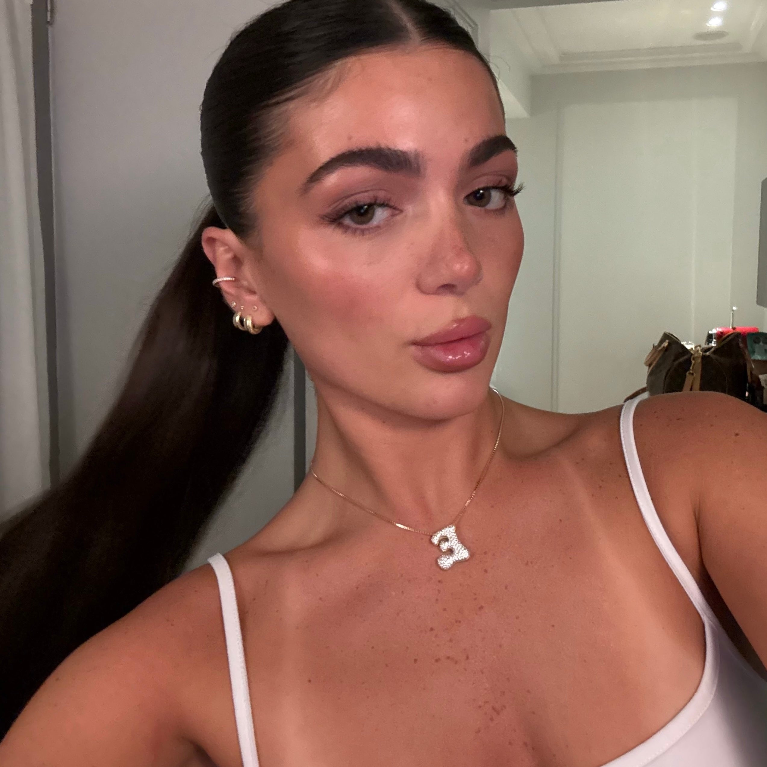 Model wearing a gold iced medium jumbo letter E necklace
