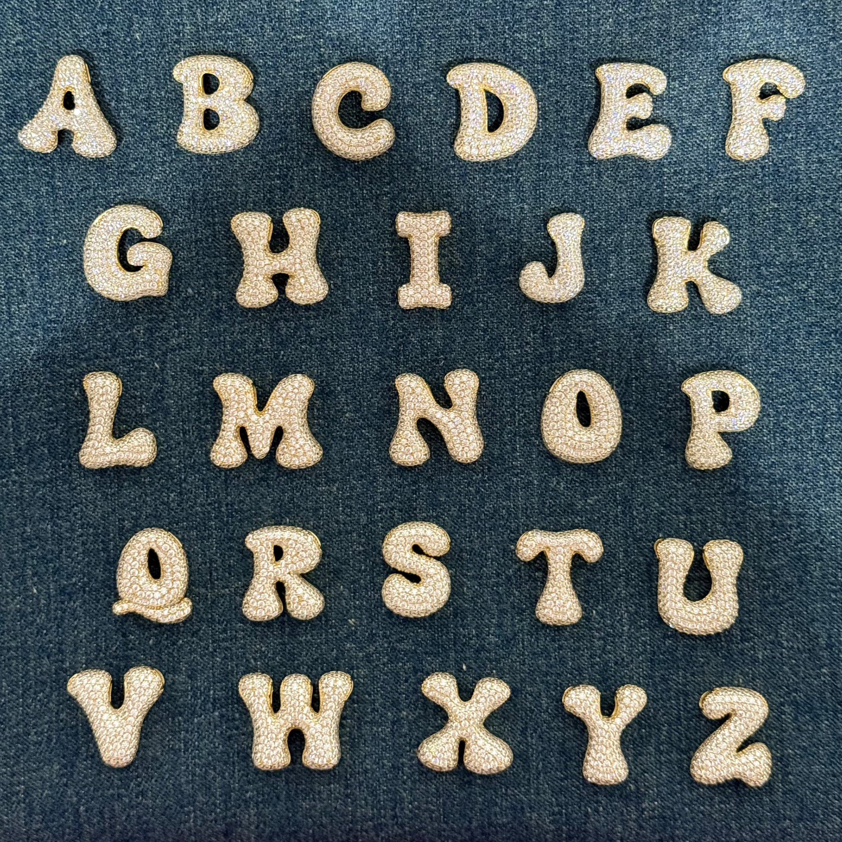 Iced medium jumbo letters A to Z laid out on denim