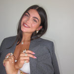 Woman in a grey blazer wearing an iced medium jumbo letter necklace