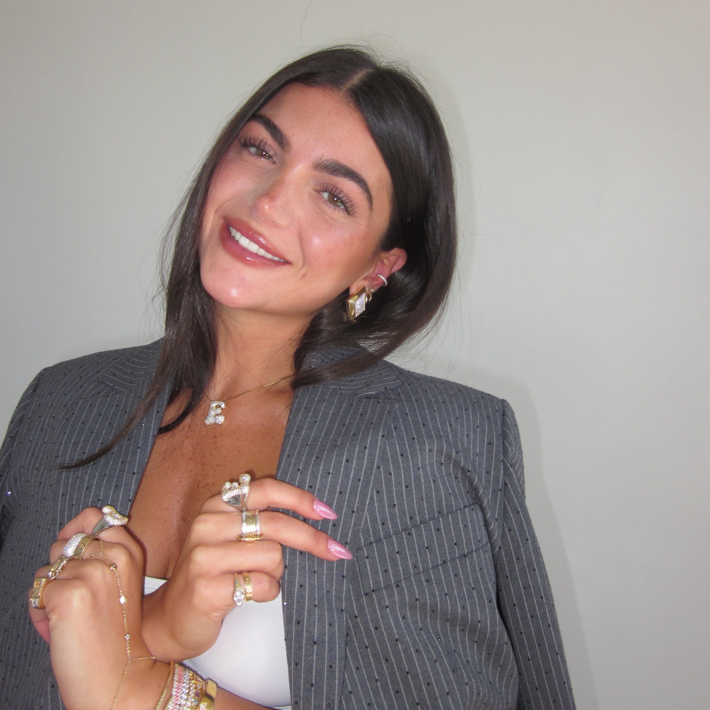 Woman in a grey blazer wearing an iced medium jumbo letter necklace