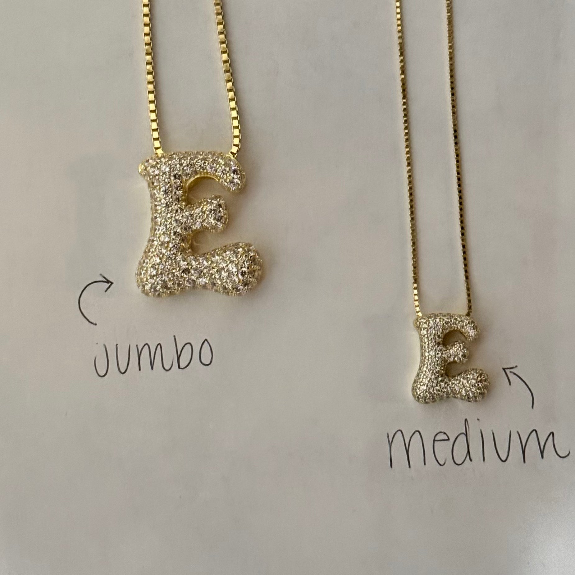 Jumbo and medium iced letter E necklaces side by side to compare sizes