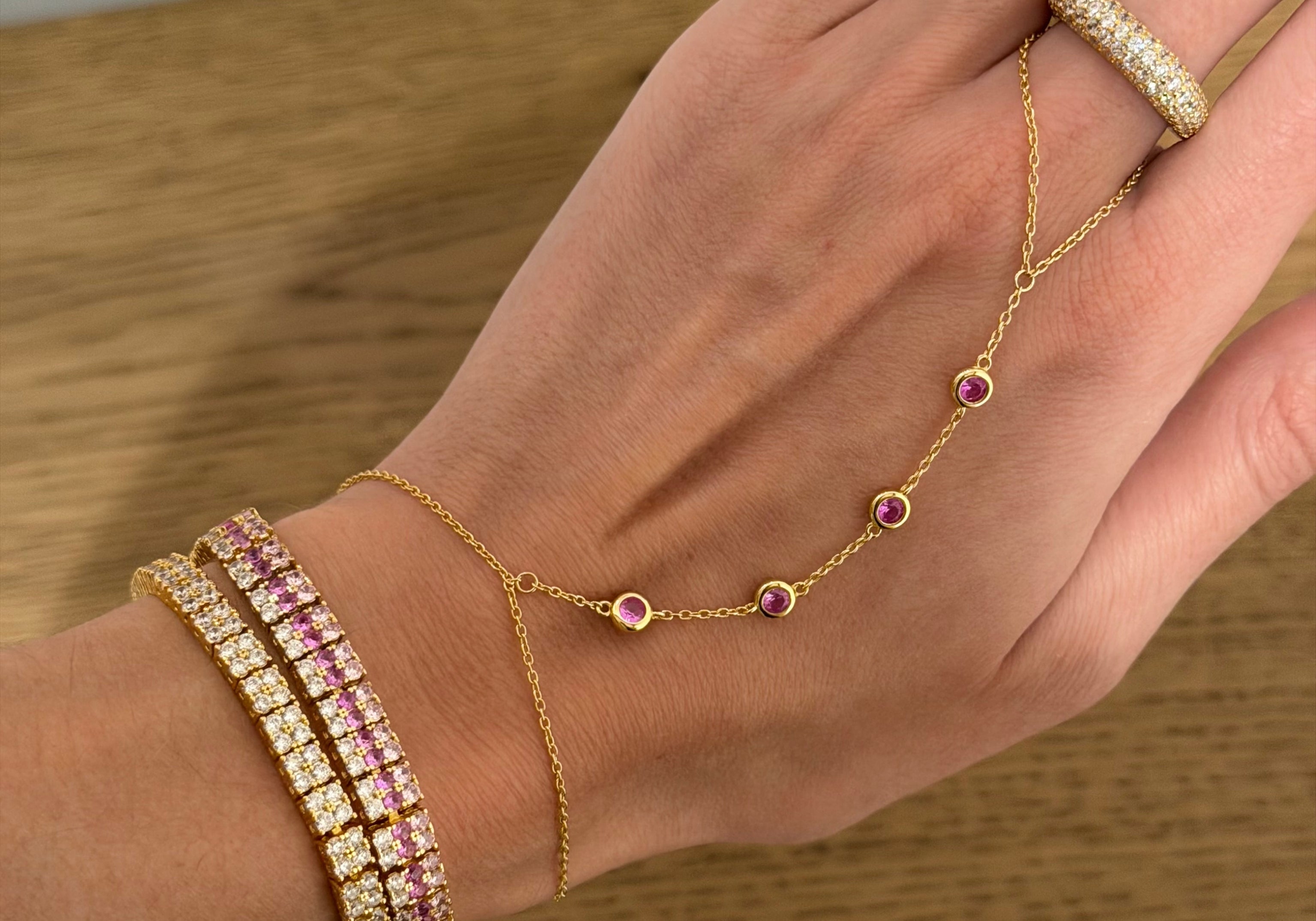 Hand wearing the Iced Kaete Pave Pinky Ring with a hand chain and pink tennis bracelets