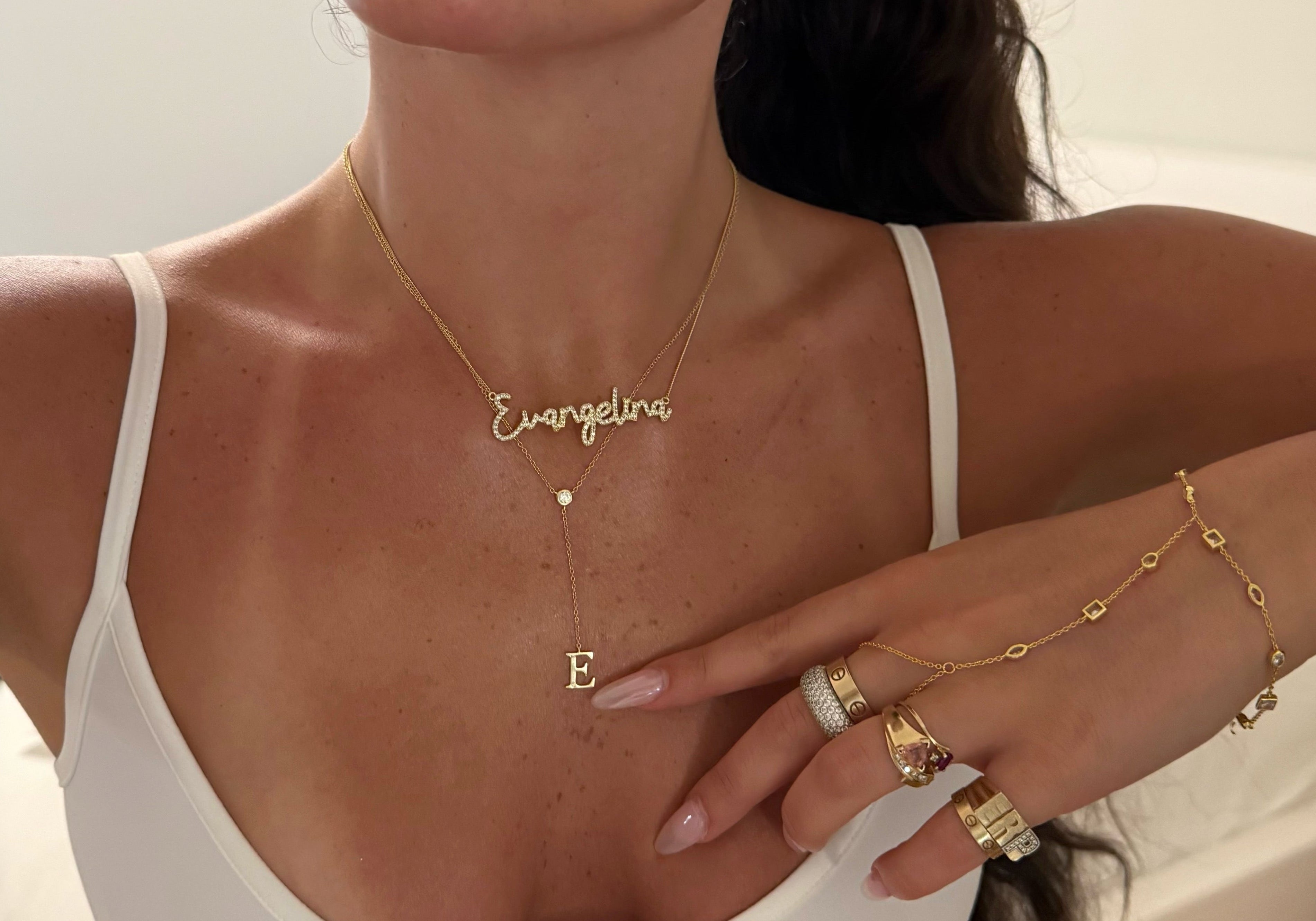 Model wearing a gold lariat letter necklace layered with a name necklace