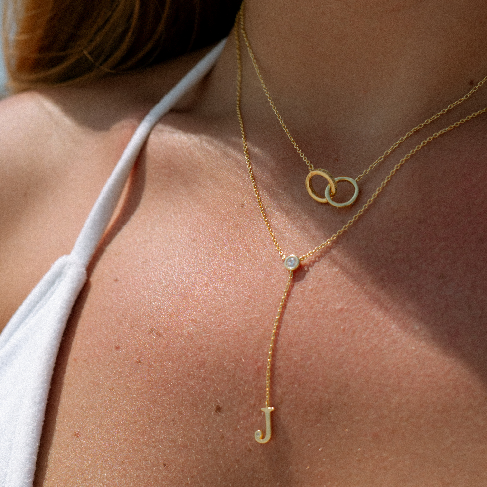 Gold lariat initial J necklace layered with a linked circle necklace