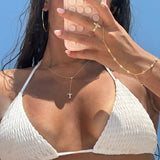Model wearing a gold lariat letter necklace with a hand chain