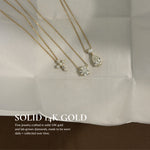 Solid 14K gold EP Timeless necklaces on white linen, including the Mini Diamond Cross Necklace