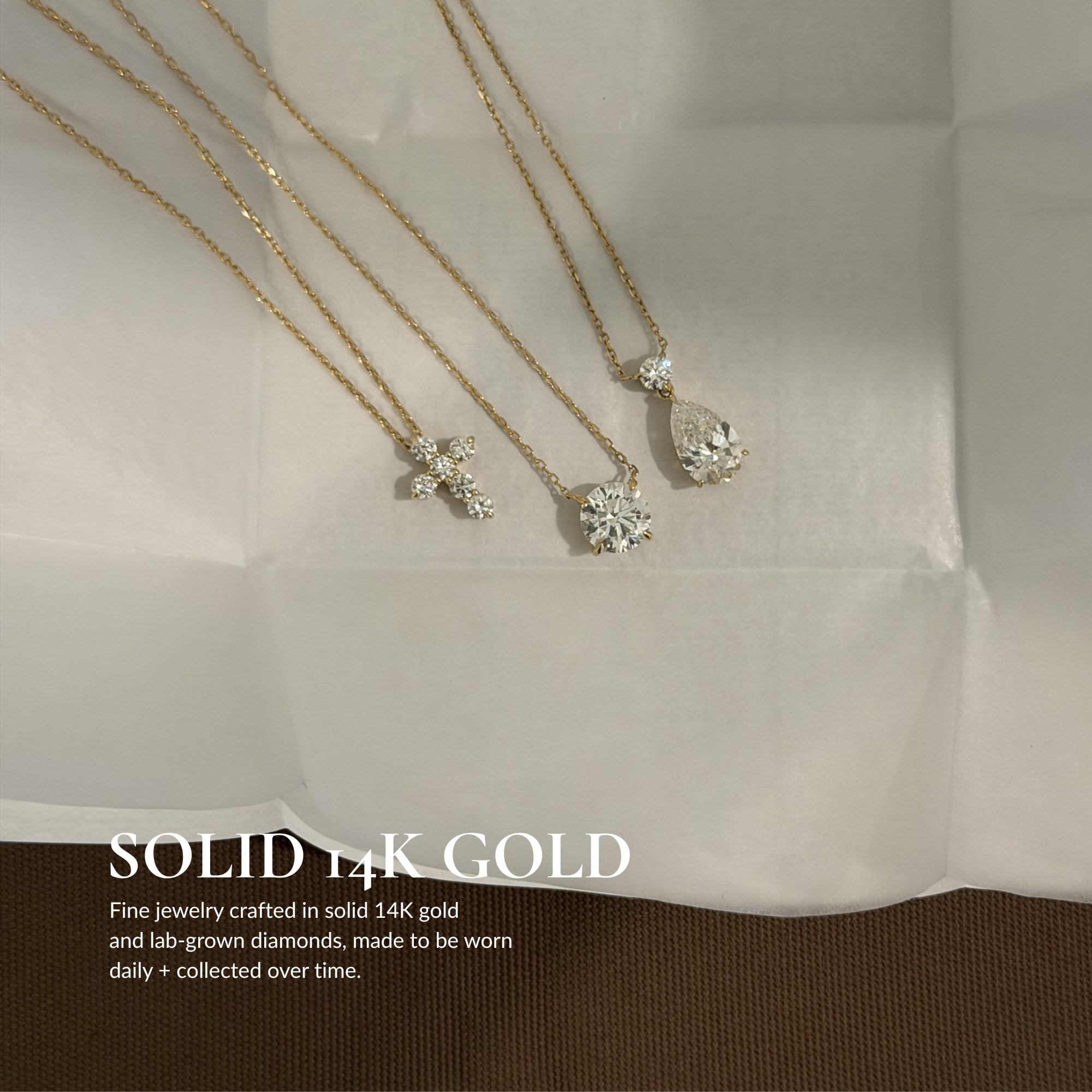 Solid 14K gold EP Timeless necklaces on white linen, including the Mini Diamond Cross Necklace