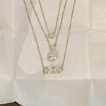 Layered EP Timeless 14K solid gold necklaces on linen, including the Multi Shape Diamond Necklace