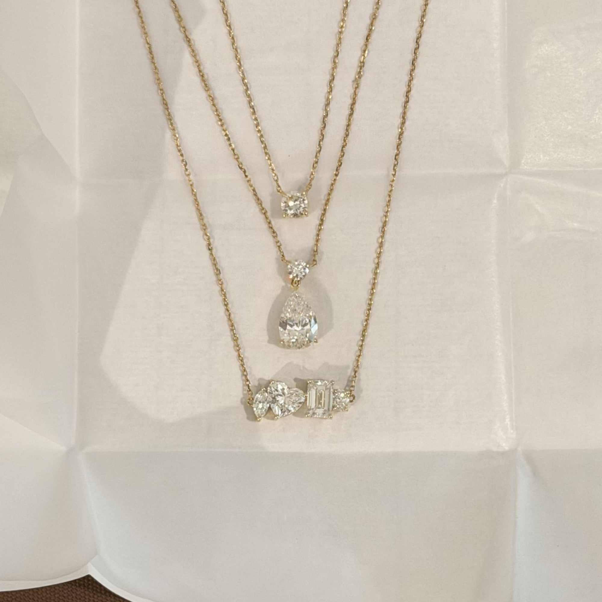 Layered EP Timeless 14K solid gold necklaces on linen, including the Multi Shape Diamond Necklace